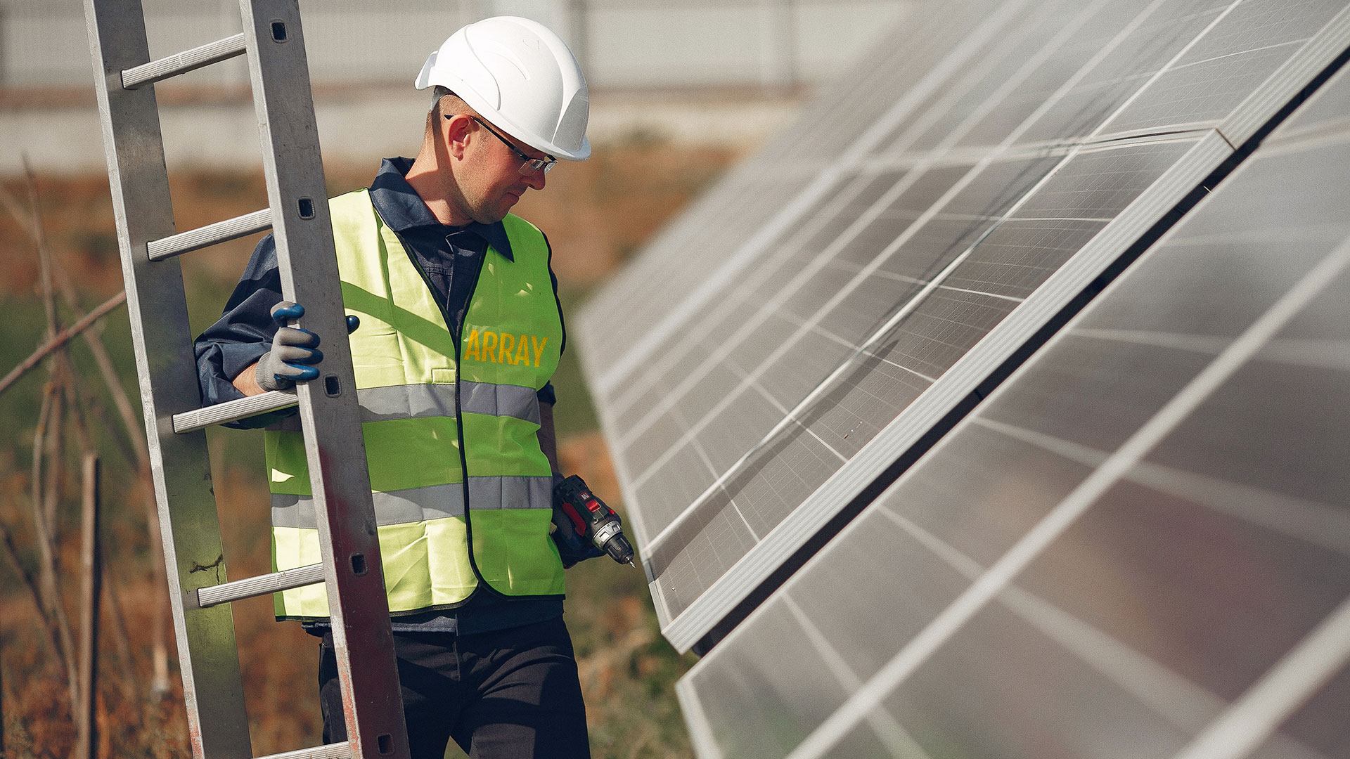 Man in a white helmet near a solar panel